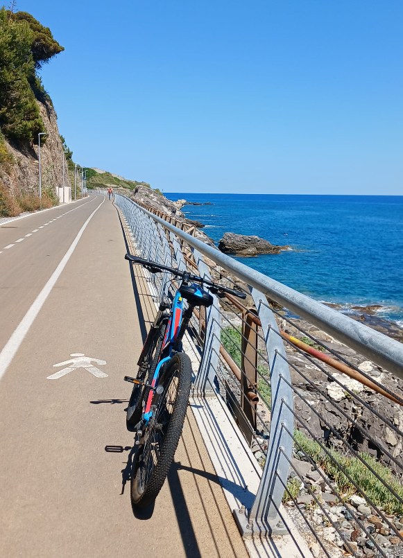 La ciclabile della Riviera dei Fiori a picco sul mare, con una bici in sosta lungo il parapetto