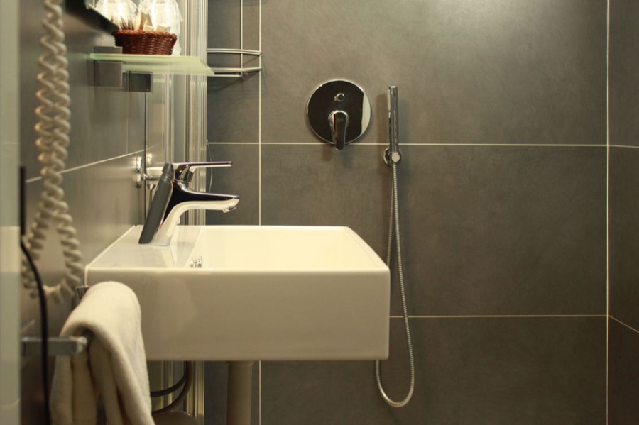 Il bagno privato moderno con doccia e rivestimenti grigi